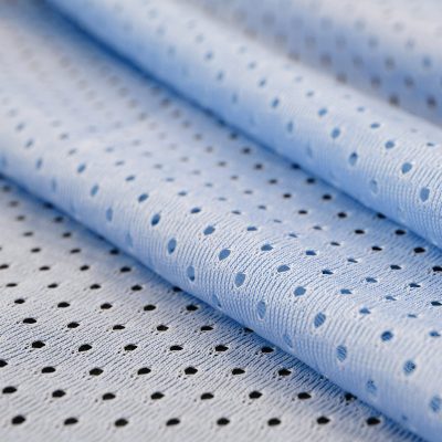 Blue mesh sport wear fabric textile pattern background. Blue color football jersey clothing fabric texture sports wear. Breathable porous poriferous material air ventilation with small holes