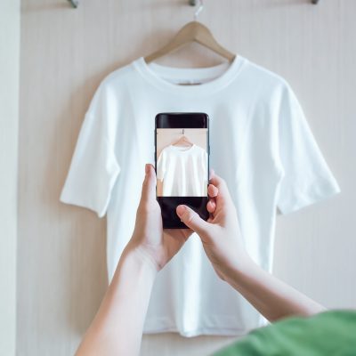 Woman is taking photo on smartphone of used clothing for resale or charity